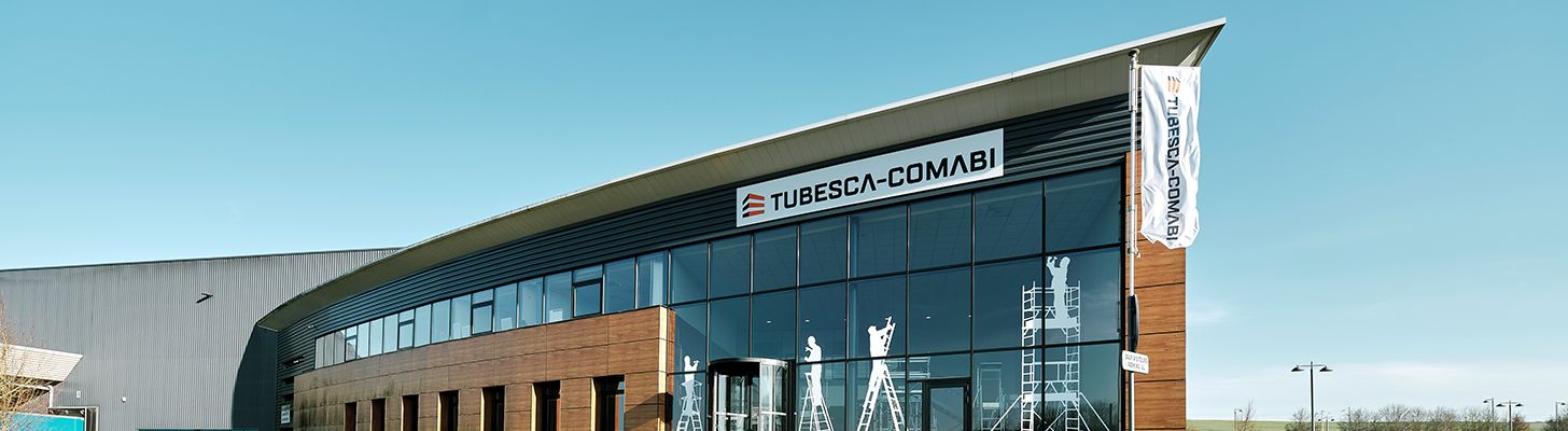 Modern building with a curved glass facade and "TUOMINEN OY" sign.