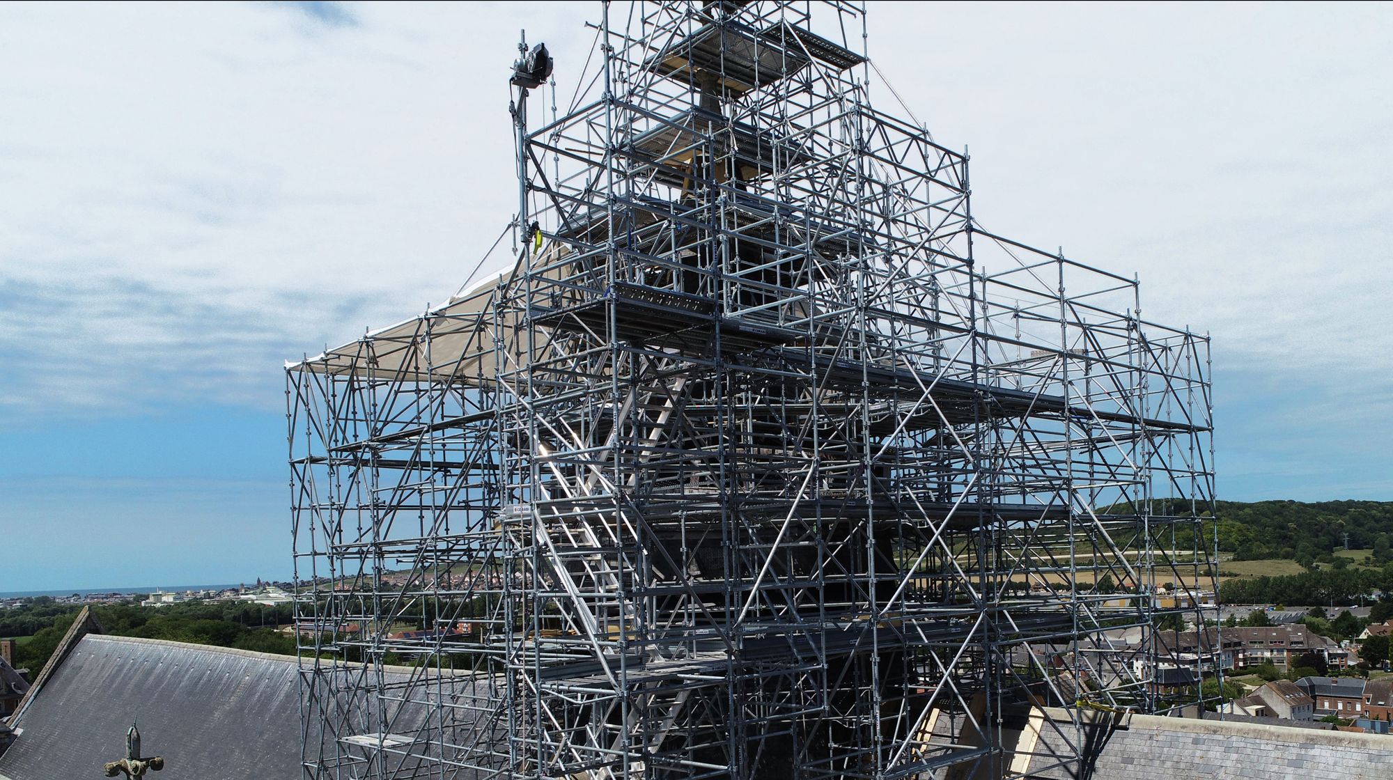 Extensive metal scaffolding surrounds a tall church tower, likely for restoration work.