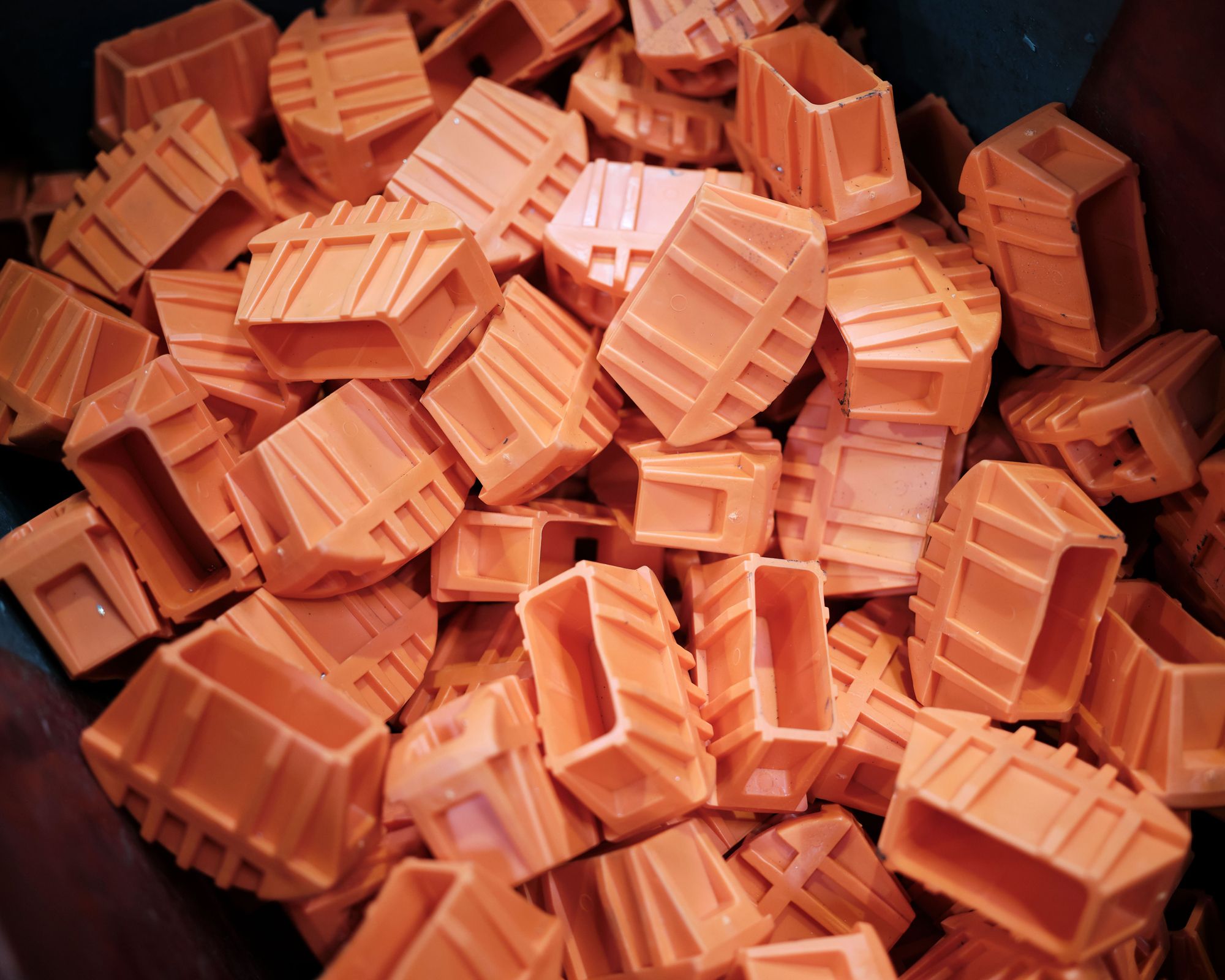 A large pile of small, orange, miniature plastic chests or containers.