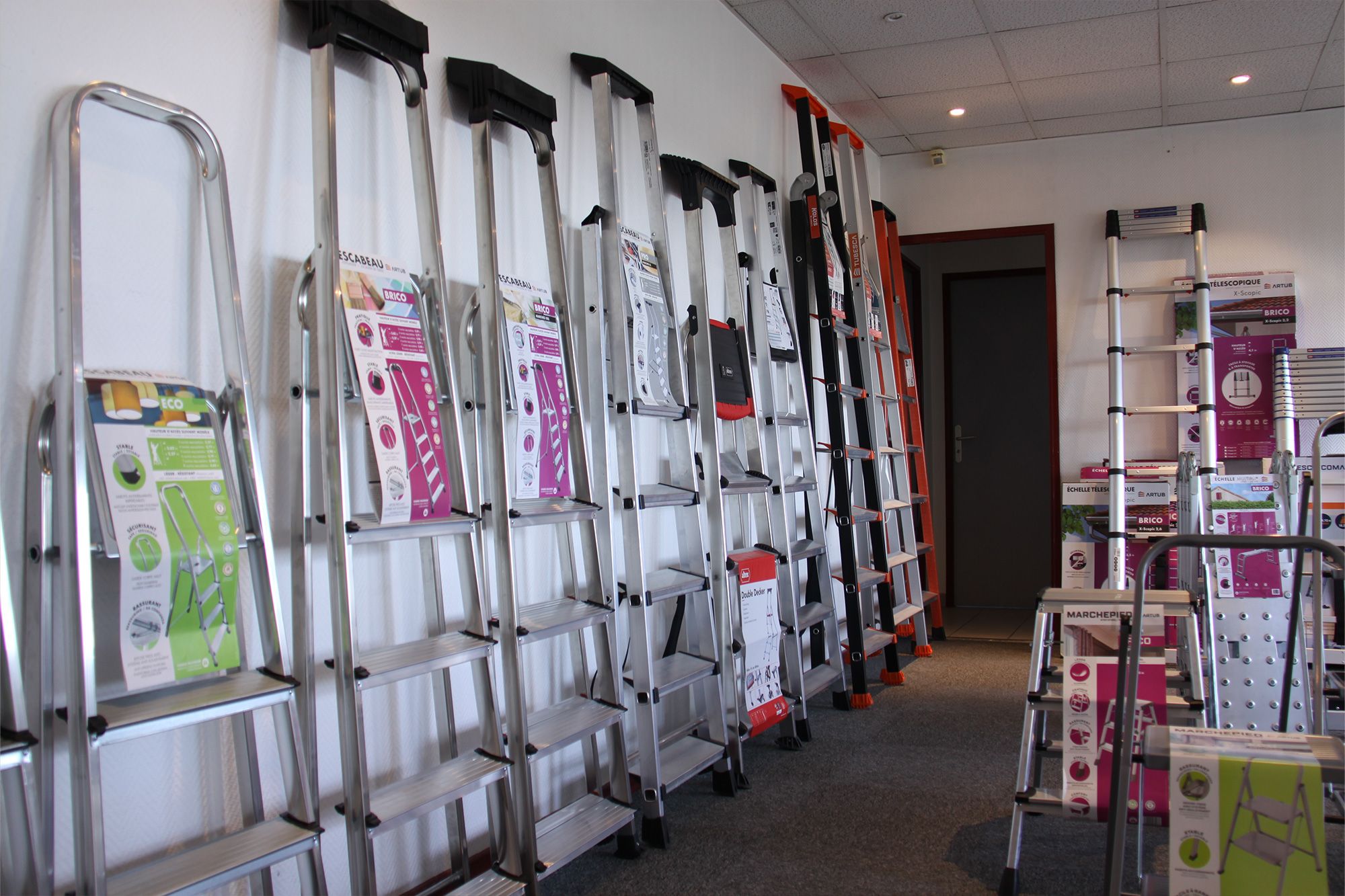 Various aluminum ladders of different types neatly displayed for sale in a hardware store.