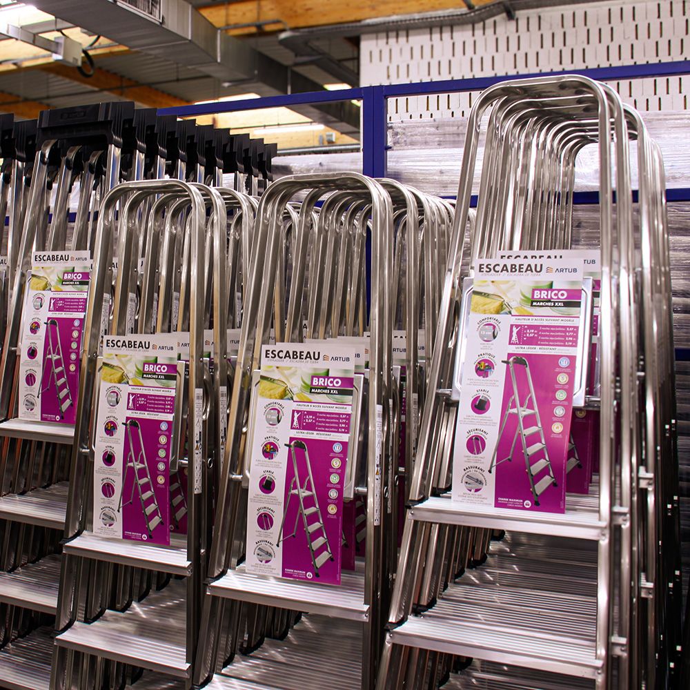 Rows of new silver step ladders displayed in a hardware store aisle with product tags.