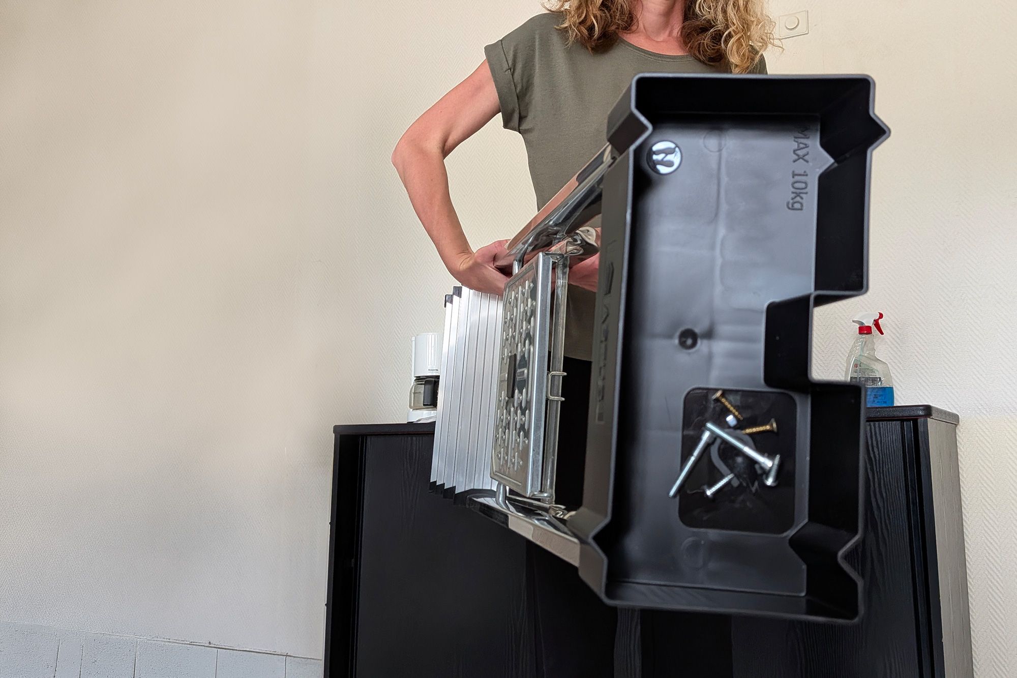 Person in green shirt holds a large, empty black computer case.